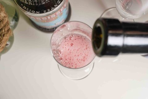 Champagner wird in ein Glas mit Cassis gegossen – klassische Zubereitung eines Kir Royal