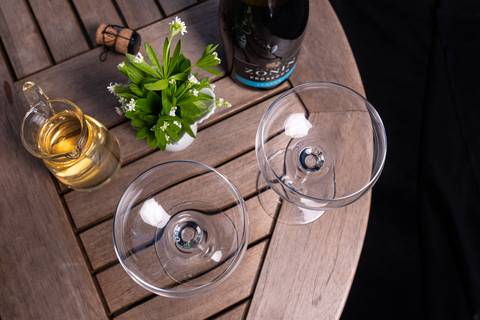Zwei leere Gläser, Waldmeister-Weißwein und Prosecco stehen bereit