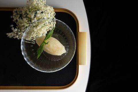 Holundersorbet mit Minze im Glasschälchen, daneben Holunderblüten