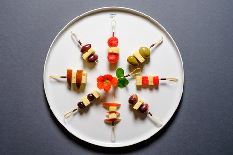 Käsespieße mit Oliven und Tomaten auf weißem Teller