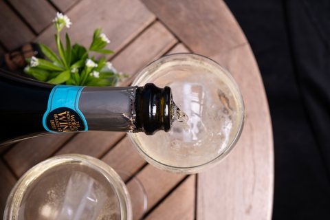 Prosecco wird in das Glas mit Waldmeisterbowle gegossen